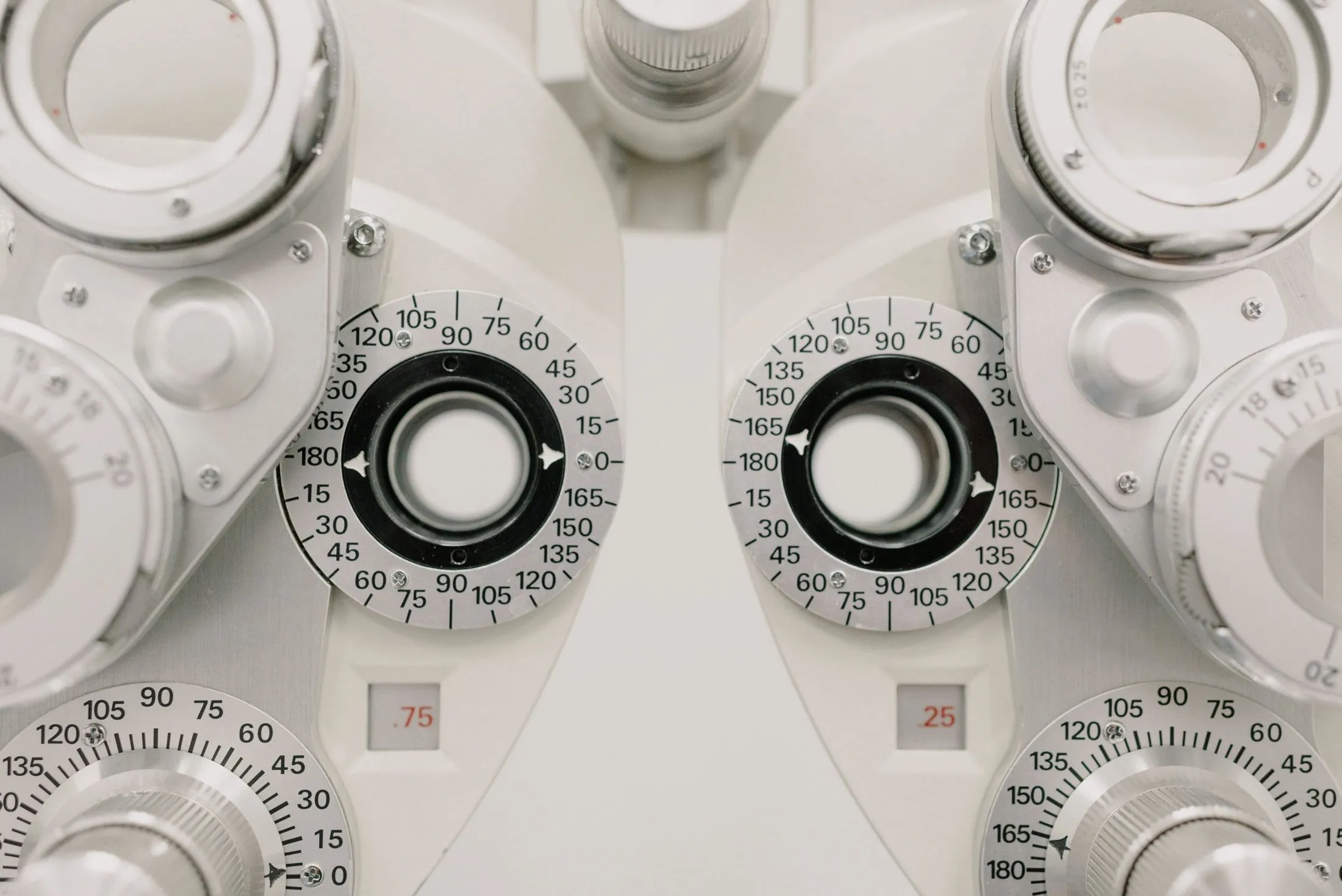 Close-up of the dials and lens apertures of a white phoropter